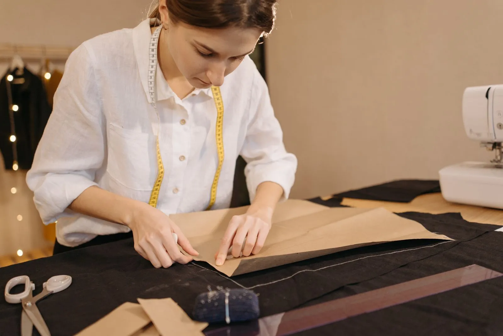 A female fashion designer measuring and cutting fabric in a dressmaking workshop.